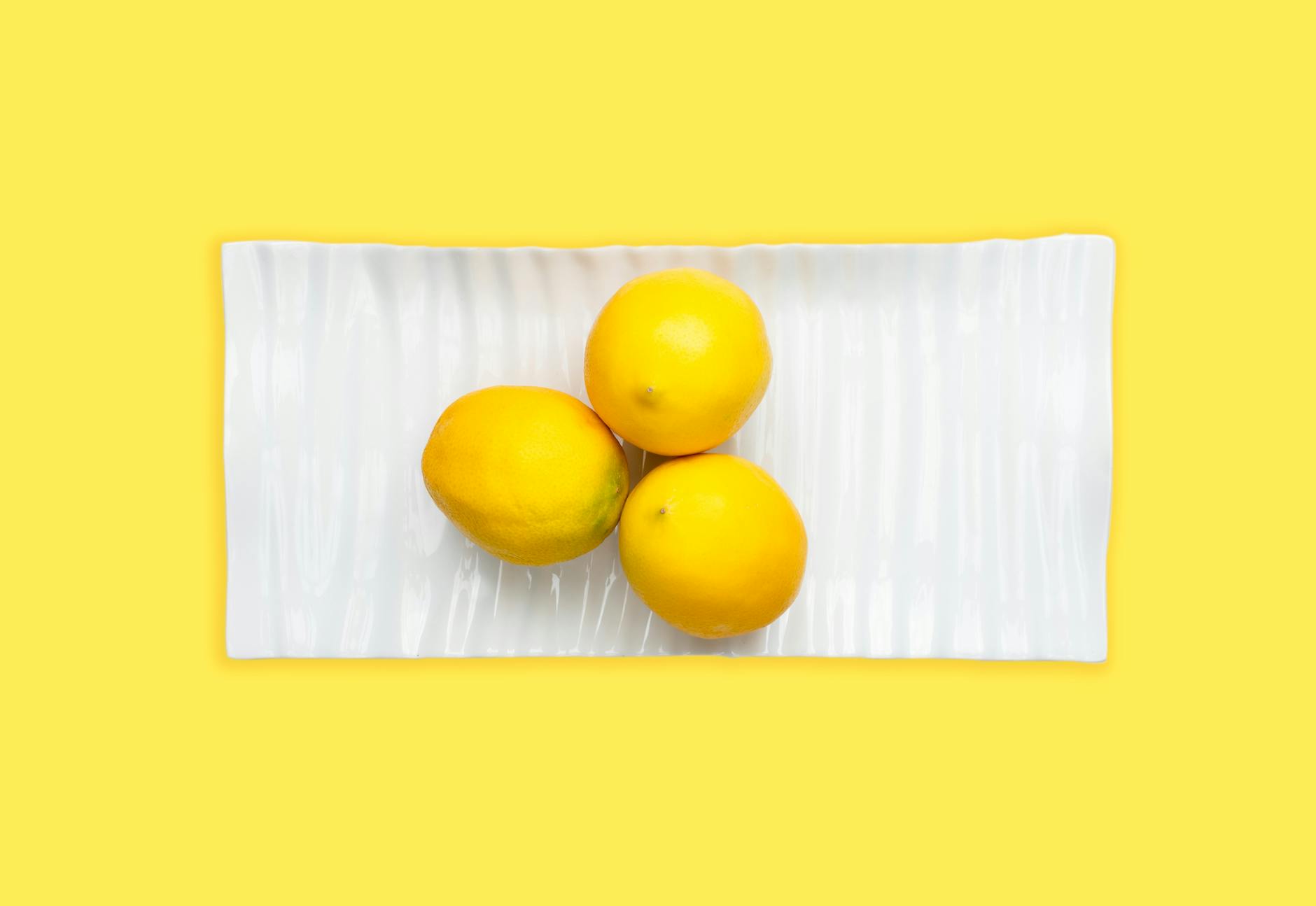 Frische gelbe Zitronen auf pastellgrünem Hintergrund, symbolisiert Frische und den Neuanfang mit dem Lemon-Vibrator