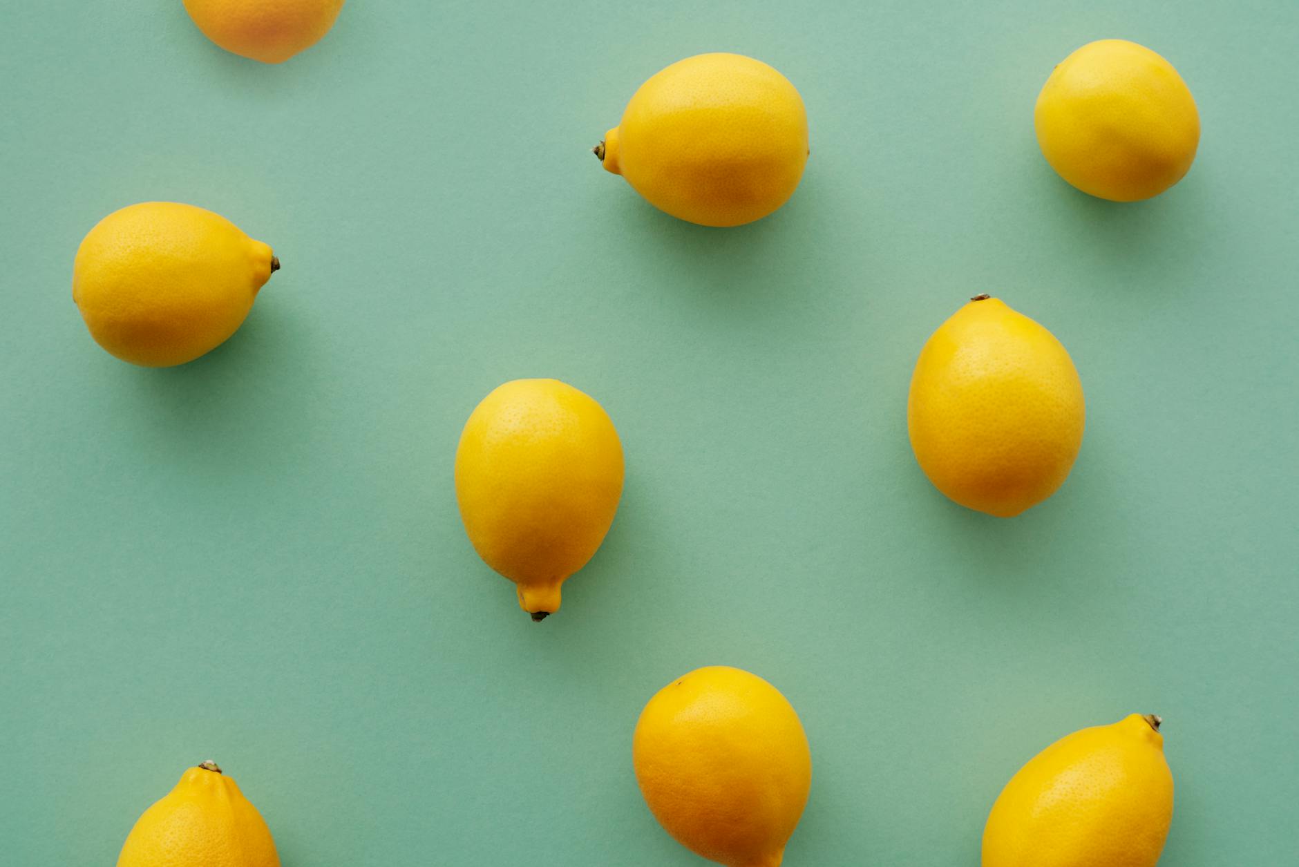 Frische gelbe Zitronen auf pastelgrünem Hintergrund, Symbol für Frische und Regeneration