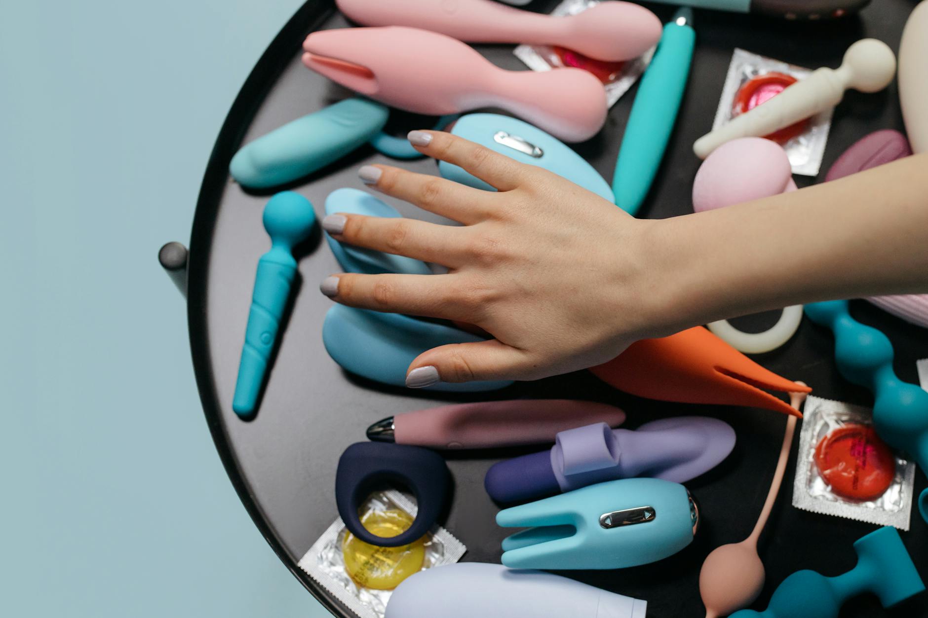 Hand hält einen modernen orange Vibrator vor lila Hintergrund, zeigt zeitgenössische Sinnlichkeit