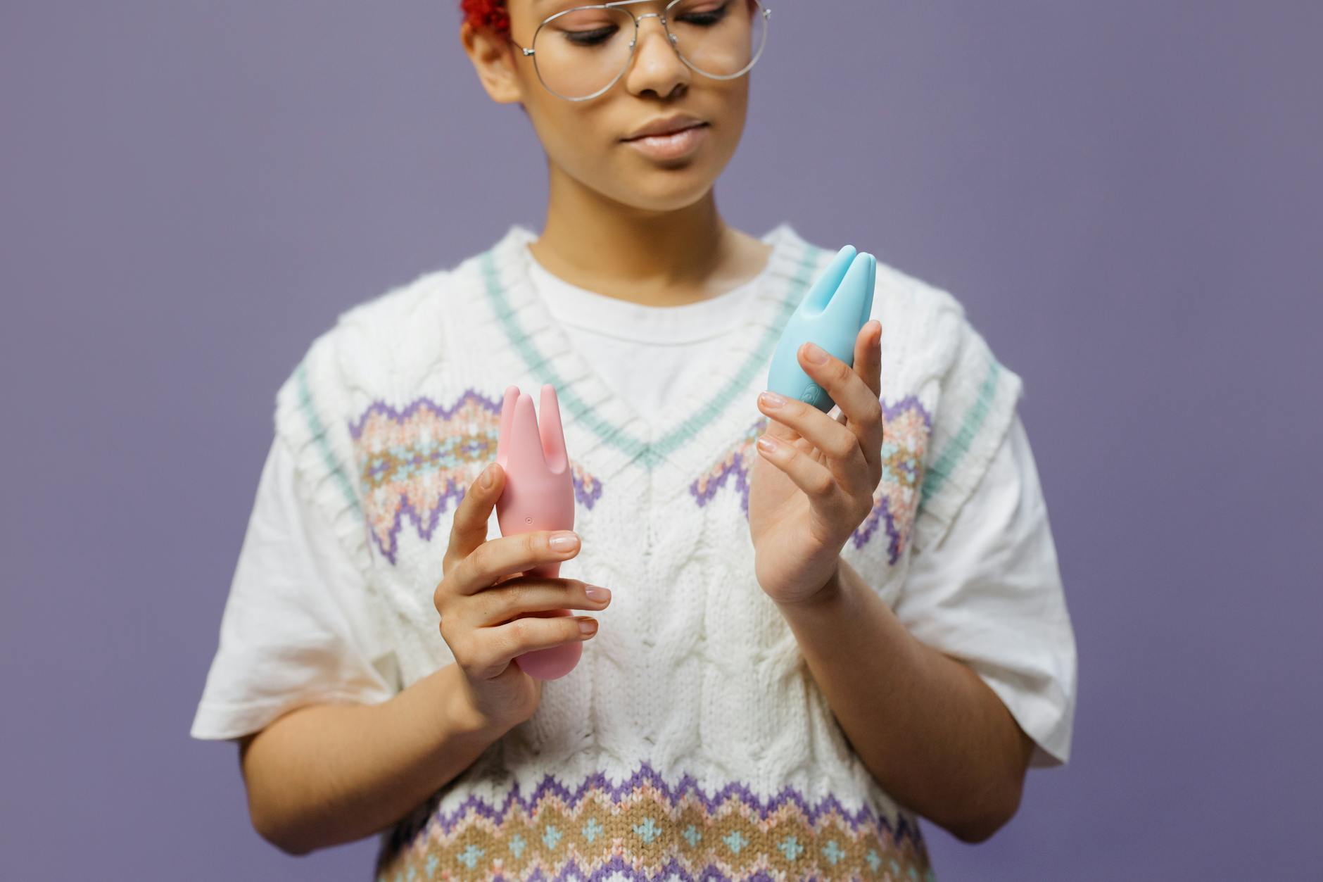 Frau mit Brille hält nachdenklich einen blauen und rosa Lemon-Vibrator