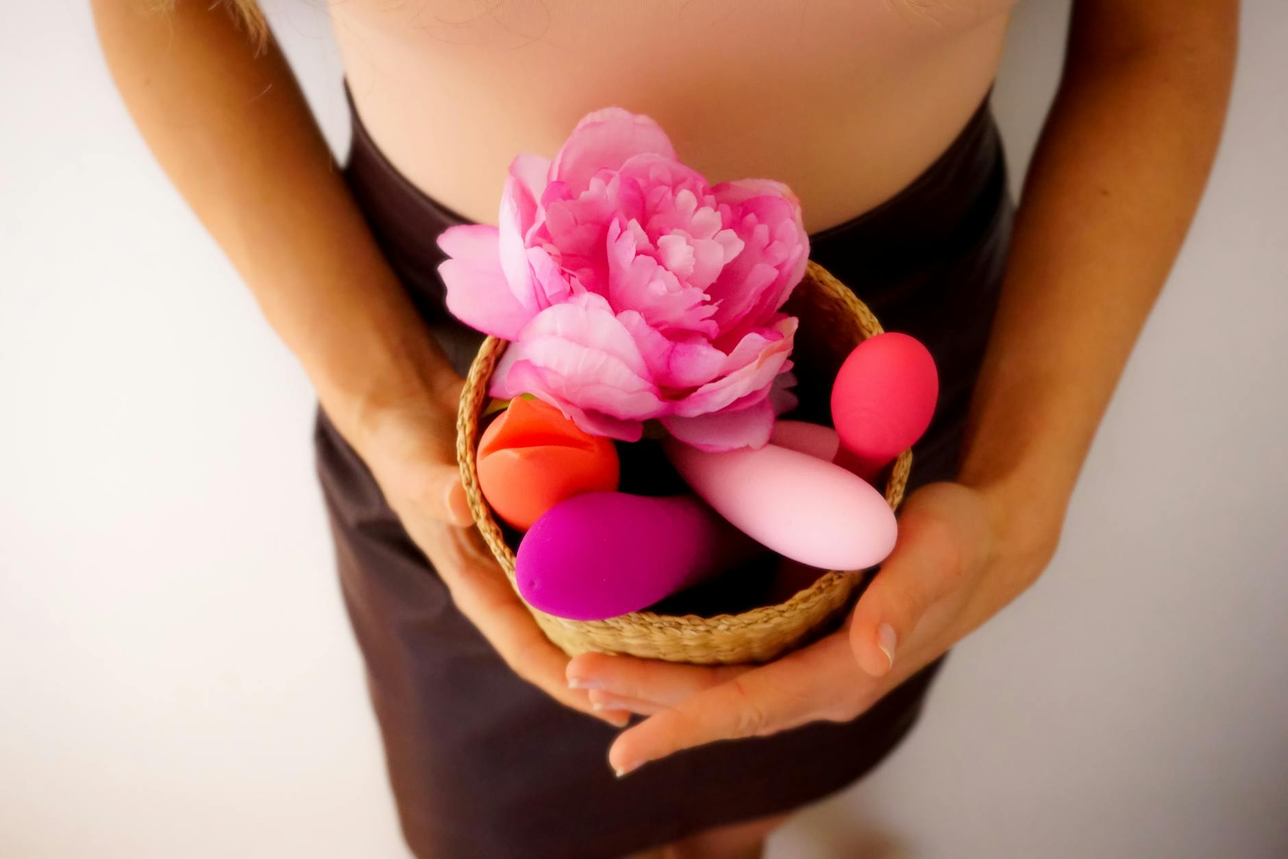 Hand mit weißen Nägeln, die eine Zitrone auf rosa Hintergrund hält, umgeben von drei weiteren Zitronen